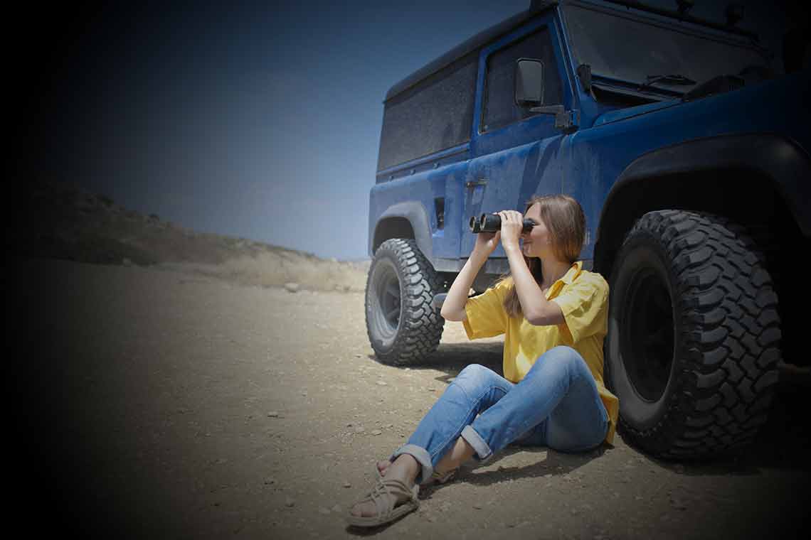Women next to jeep looking through binoculars